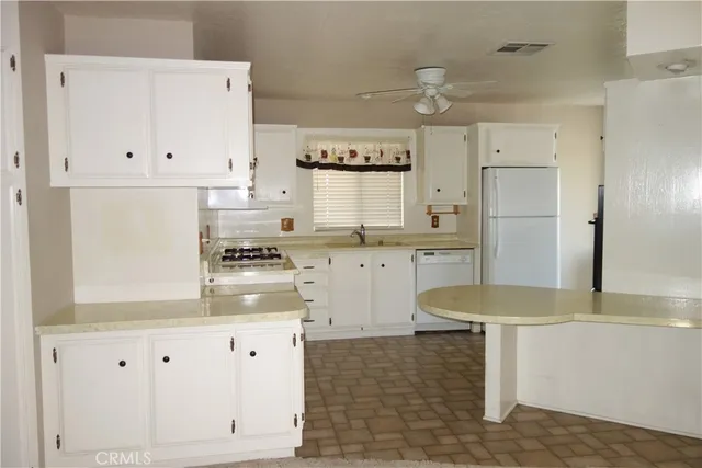 a kitchen with granite countertop white cabinets and white appliances