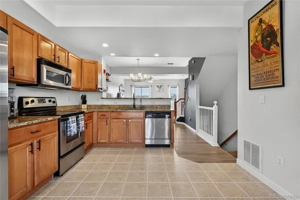 a kitchen with stainless steel appliances granite countertop a sink dishwasher stove top oven and refrigerator