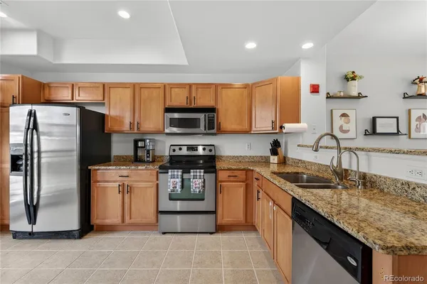 a kitchen with granite countertop a refrigerator and a stove top oven