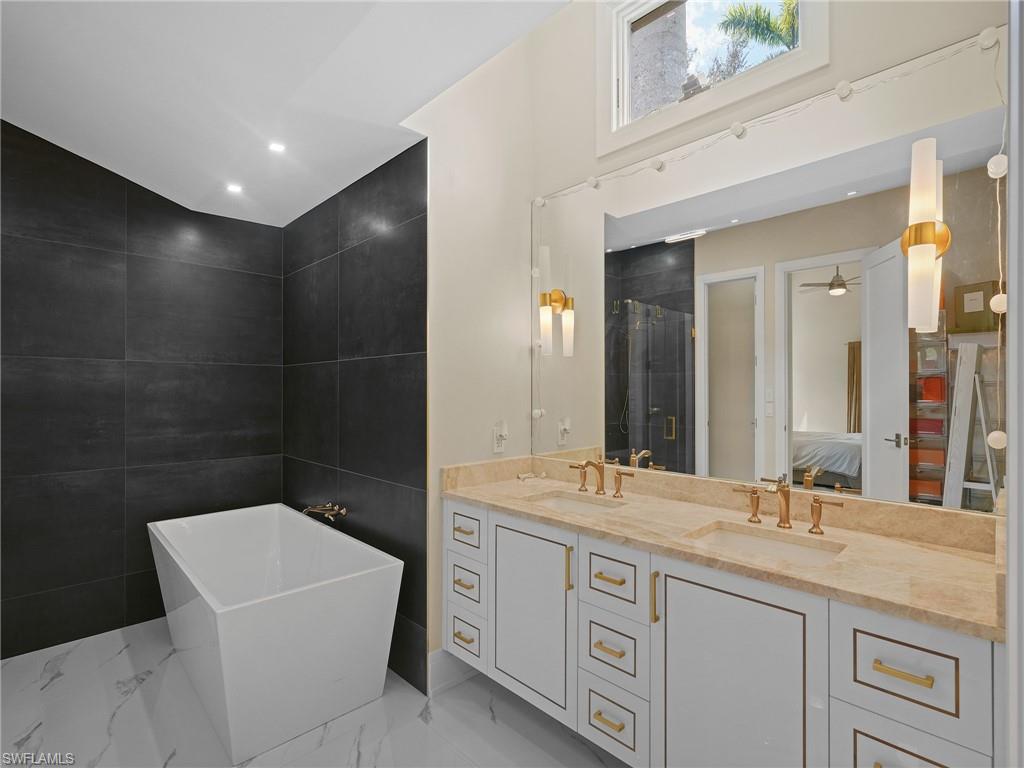 2140 Harlans Run Naples, FL 34105 - Photo 21 of 37 a bathroom with a granite countertop sink a toilet a mirror and bathtub