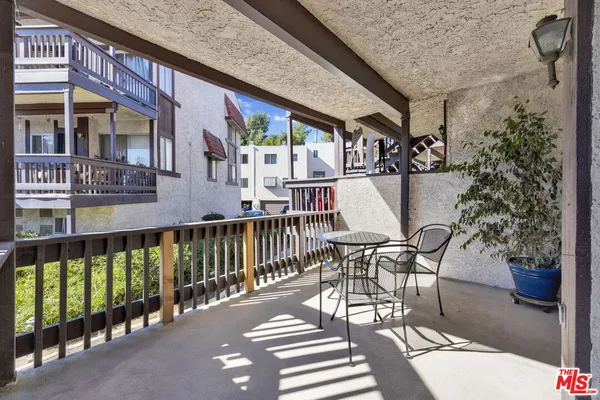 a view of a patio with table and chairs potted plants with wooden floor and fence