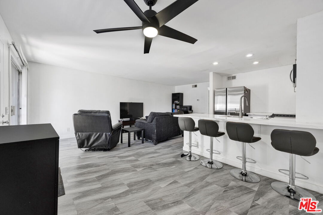12330 Osborne Street, Unit 77 Pacoima, CA 91331 - Photo 2 of 32 a kitchen with stainless steel appliances kitchen island granite countertop a dining table chairs and a refrigerator