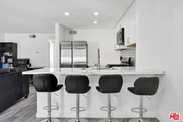 a kitchen with stainless steel appliances kitchen island granite countertop a table and chairs in it