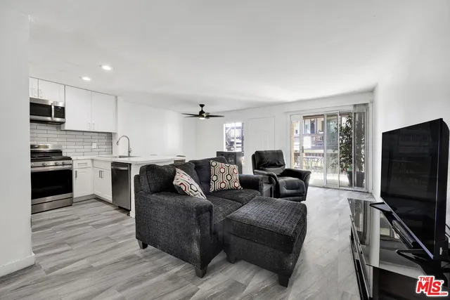 a living room with furniture a flat screen tv and kitchen view