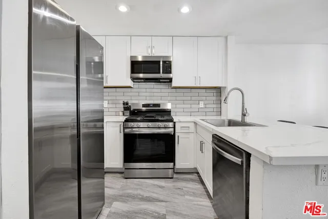 a kitchen with stainless steel appliances granite countertop a sink a stove a microwave and a refrigerator