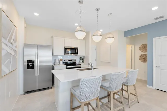 a kitchen with stainless steel appliances a table chairs refrigerator and microwave