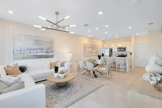 a living room with furniture kitchen view and a chandelier