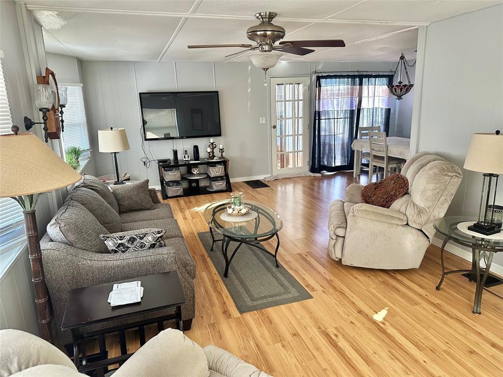 9900 Ulmerton Road, Unit 61 Largo, FL 33771 - Photo 2 of 17 a living room with furniture a flat screen tv and wooden floor