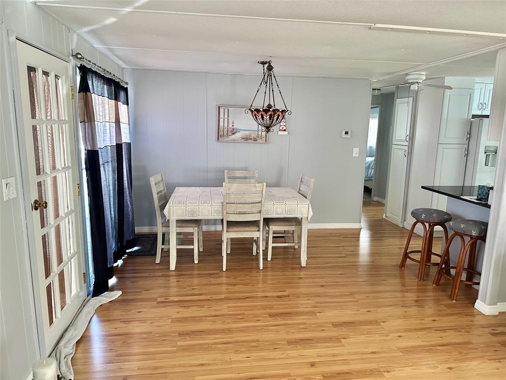 9900 Ulmerton Road, Unit 61 Largo, FL 33771 - Photo 5 of 17 a dining room with furniture a chandelier and wooden floor