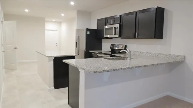 a kitchen with stainless steel appliances granite countertop a sink a microwave a refrigerator and a refrigerator