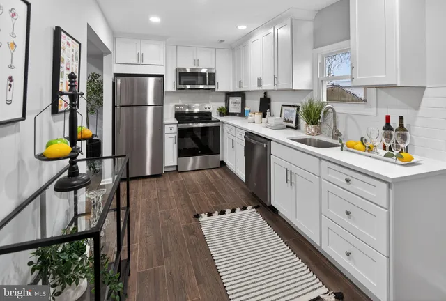 a kitchen with refrigerator a stove a sink cabinets and wooden floor