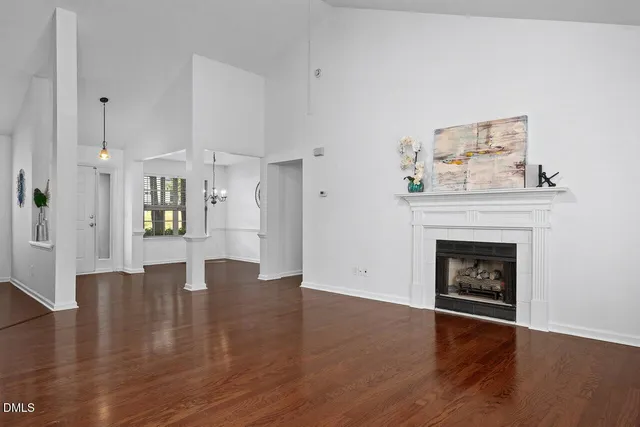 a view of an empty room with wooden floor and a fireplace