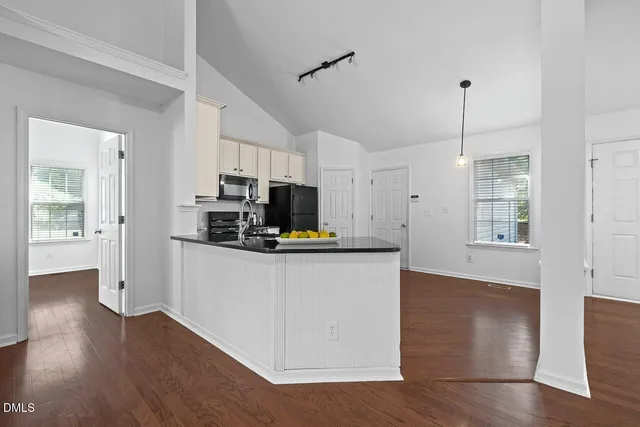 a kitchen with stainless steel appliances granite countertop a refrigerator a sink dishwasher a stove and white cabinets with wooden floor