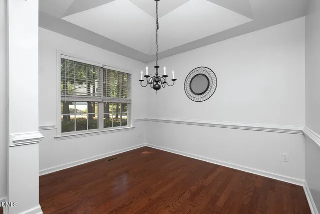 a view of an empty room with wooden floor and window