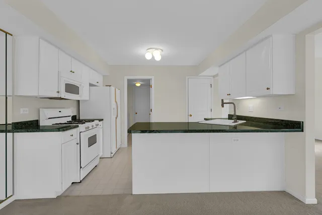 a kitchen with stainless steel appliances granite countertop a stove a sink and white cabinets