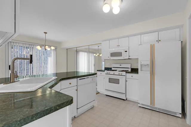 a kitchen with granite countertop a stove a sink and a refrigerator