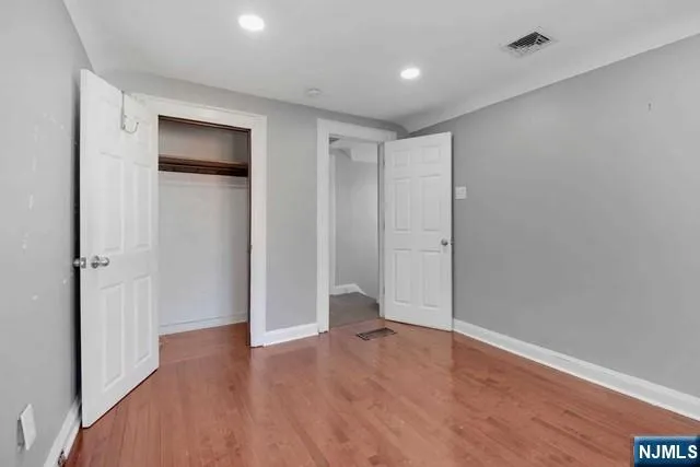 a view of an empty room with wooden floor and closet