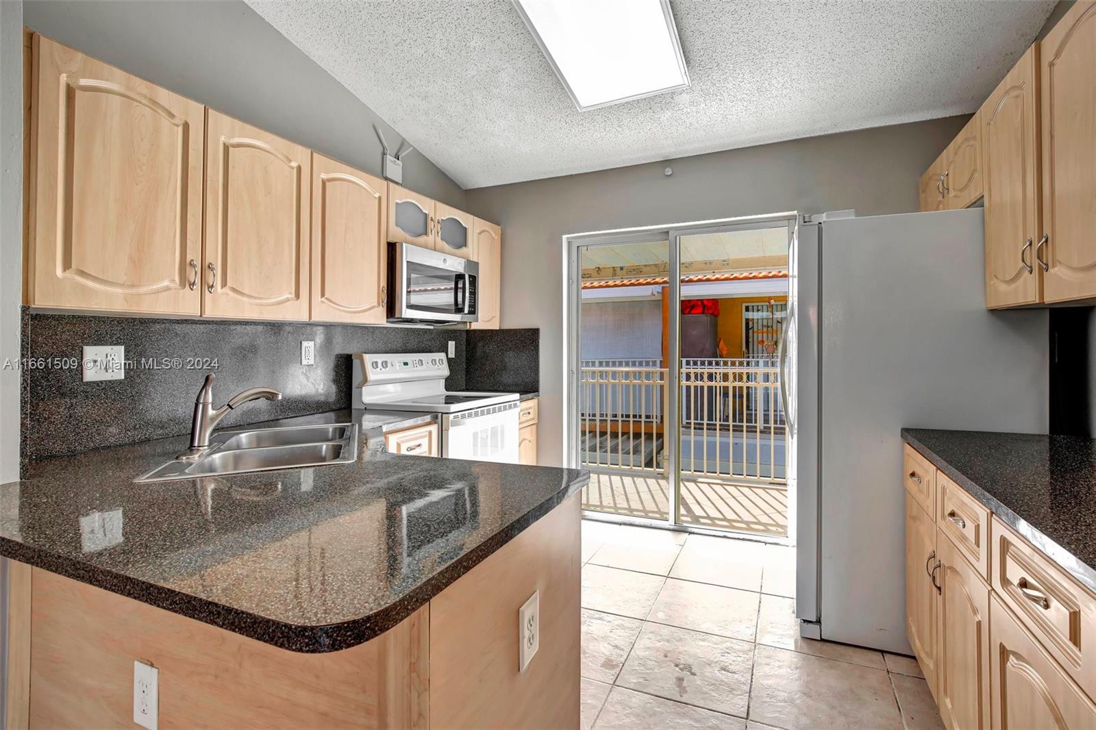 2527 West 76th Street, Unit 208 Hialeah, FL 33016 - Photo 13 of 37 a kitchen with stainless steel appliances granite countertop a sink a stove and a microwave oven with granite countertops