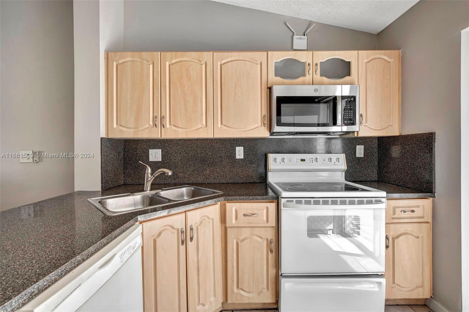2527 West 76th Street, Unit 208 Hialeah, FL 33016 - Photo 14 of 37 a kitchen with stainless steel appliances granite countertop a stove a microwave and a refrigerator