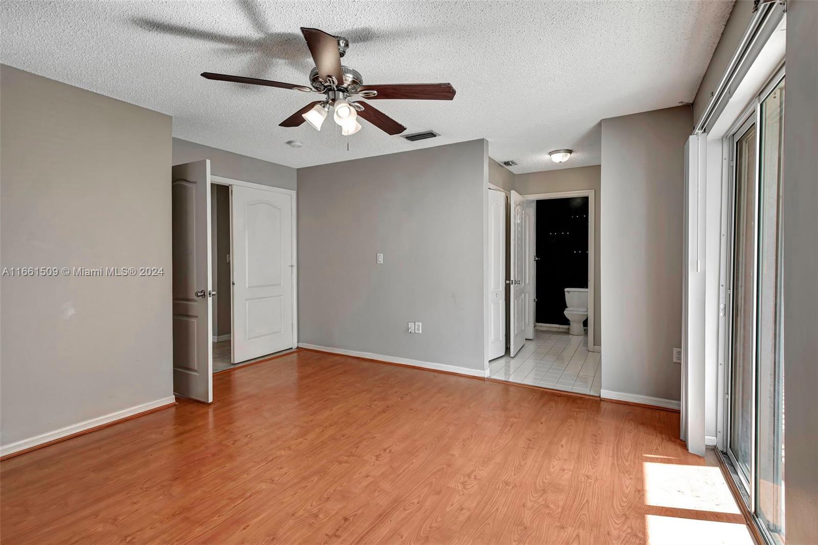 2527 West 76th Street, Unit 208 Hialeah, FL 33016 - Photo 22 of 37 an empty room with wooden floor fan and windows