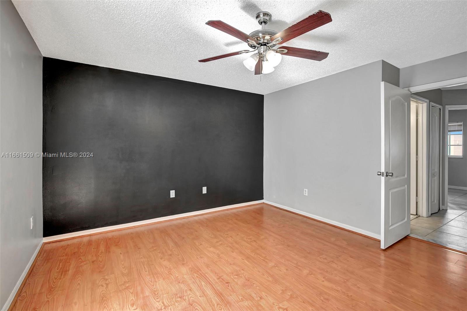 2527 West 76th Street, Unit 208 Hialeah, FL 33016 - Photo 23 of 37 an empty room with a ceiling fan and wooden floor