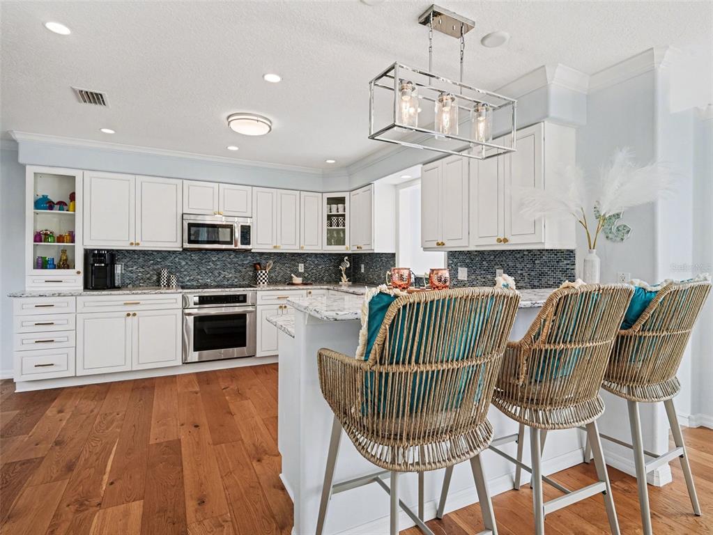 129 Hammock Road Anna Maria, FL 34216 - Photo 8 of 52 a kitchen with kitchen island granite countertop a stove a sink a oven a dining table and chairs with wooden floor
