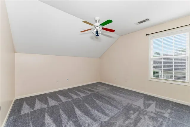 an empty room with windows and ceiling fan