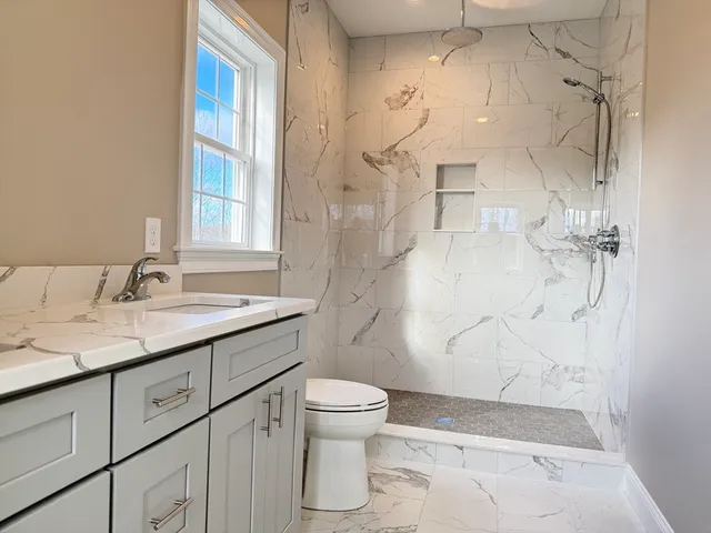 a bathroom with a granite countertop sink toilet and shower