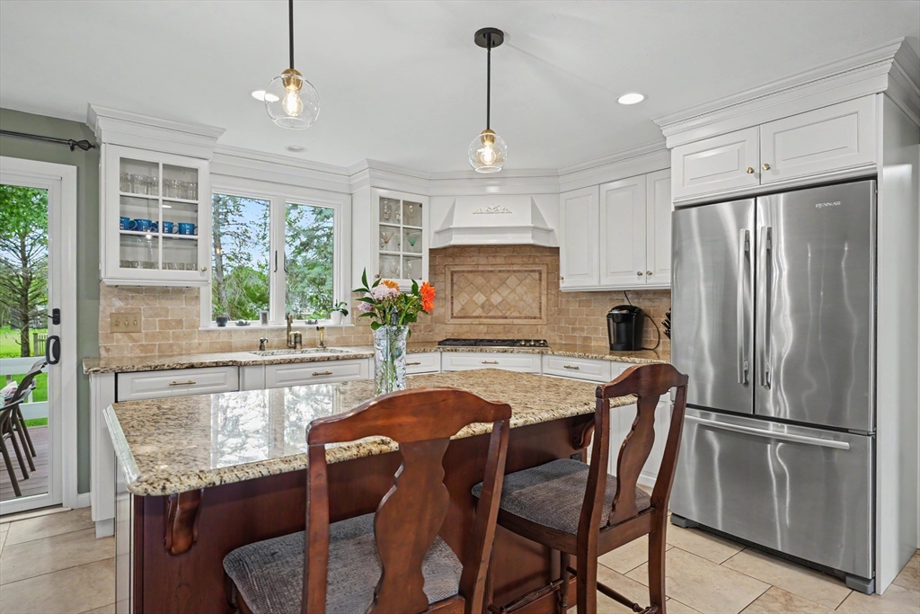 15 Lanthorn Road Northborough, MA 01532 - Photo 8 of 37 a kitchen with granite countertop a refrigerator a stove a kitchen island with a dining table and chairs