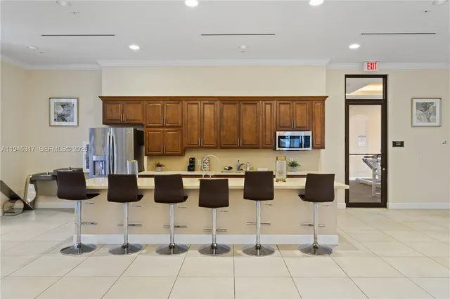 a kitchen with stainless steel appliances kitchen island granite countertop a refrigerator and chairs