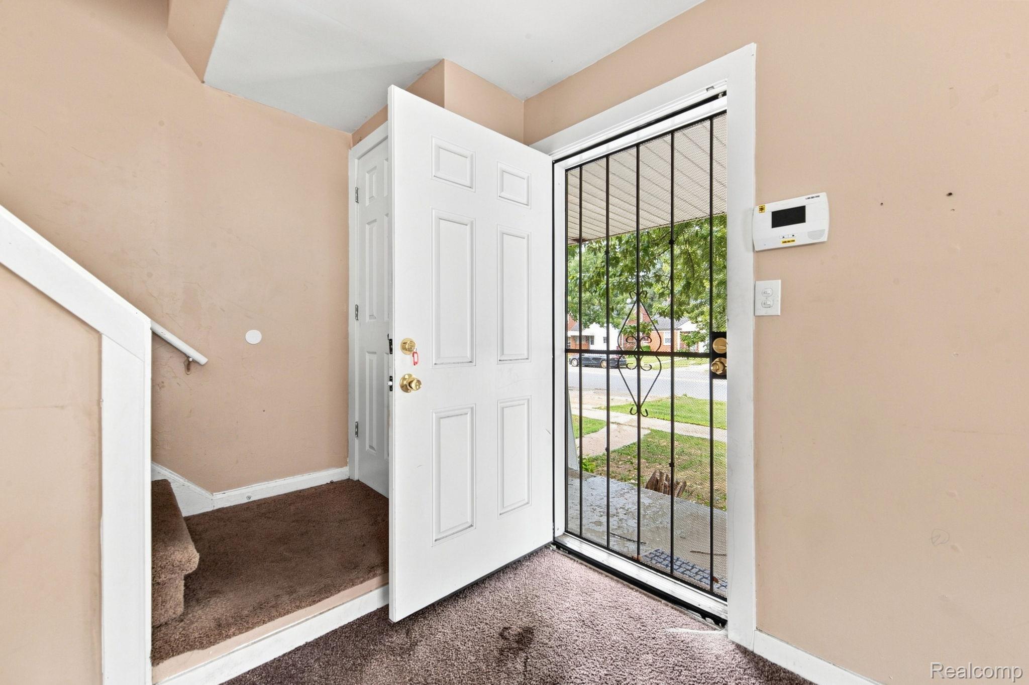 8882 Evergreen Road Detroit, MI 48228 - Photo 5 of 21 Entryway featuring a panel door with a security screen, carpeted flooring, and a staircase with a handrail