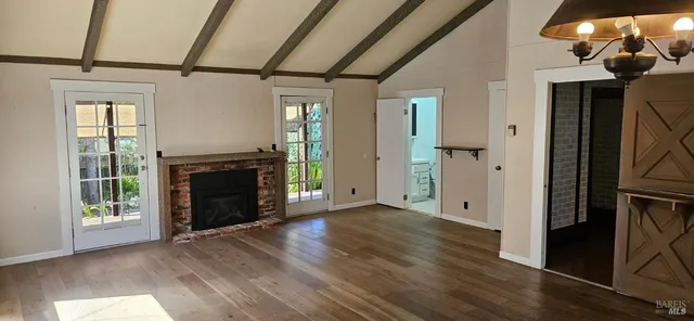 an empty room with wooden floor a fireplace and windows