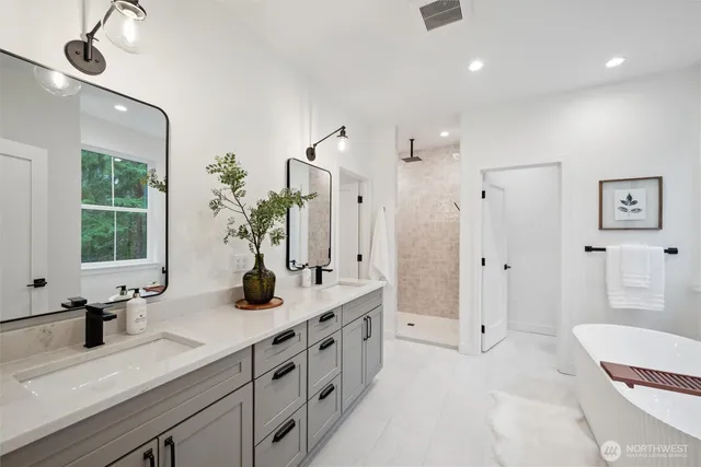 a bathroom with a double vanity sink mirror and bathtub