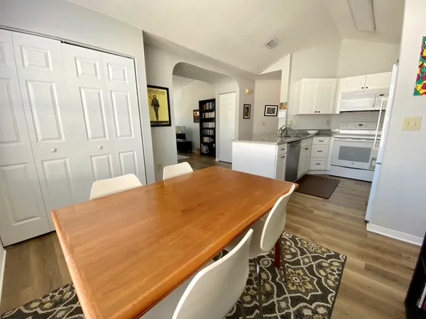 a kitchen with stainless steel appliances kitchen island granite countertop a refrigerator a stove and white cabinets with wooden floor