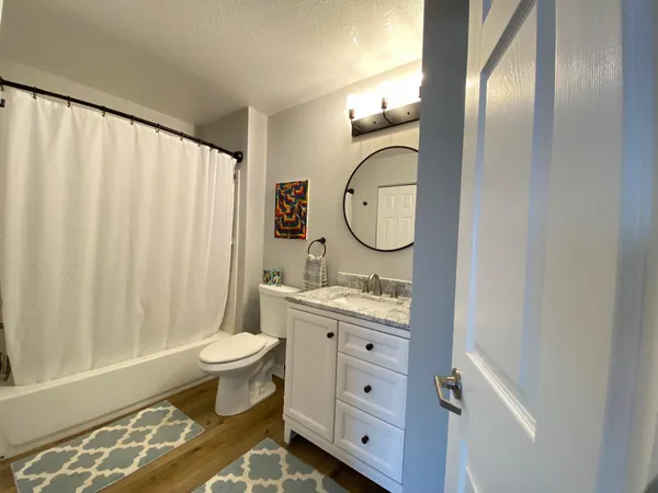 a bathroom with a toilet sink vanity granite and a mirror