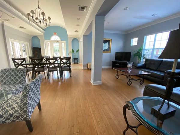 a dining room with wooden floor a chandelier a glass table and chairs