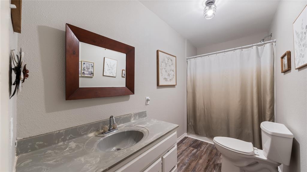 14260 North 3rd Street Scurry, TX 75158 - Photo 13 of 13 Full bathroom featuring vanity, dark wood finished floors, a textured wall, and a shower with curtain