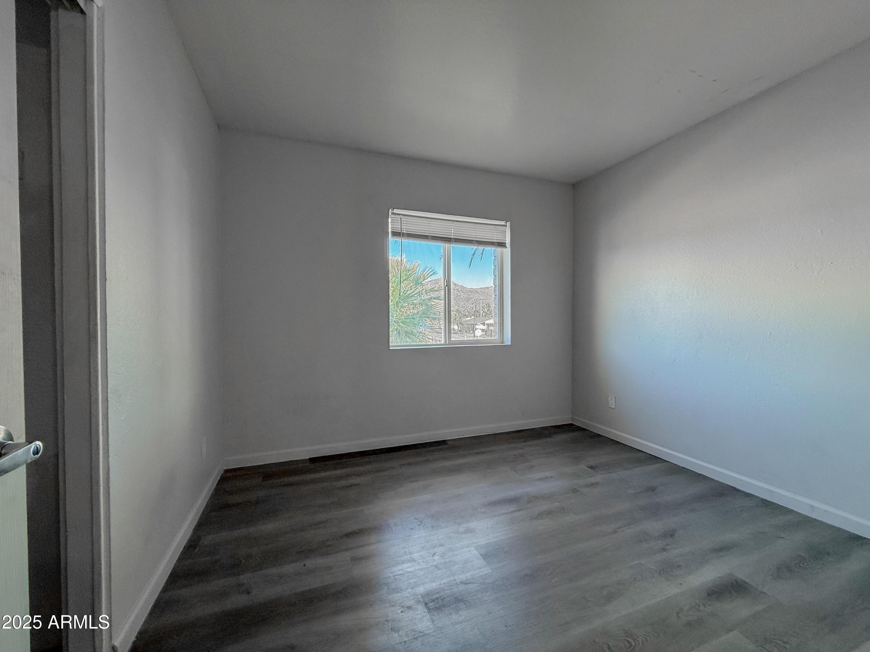 1703 West Mountain View Road, Unit 13 Phoenix, AZ 85021 - Photo 6 of 12 an empty room with wooden floor and windows