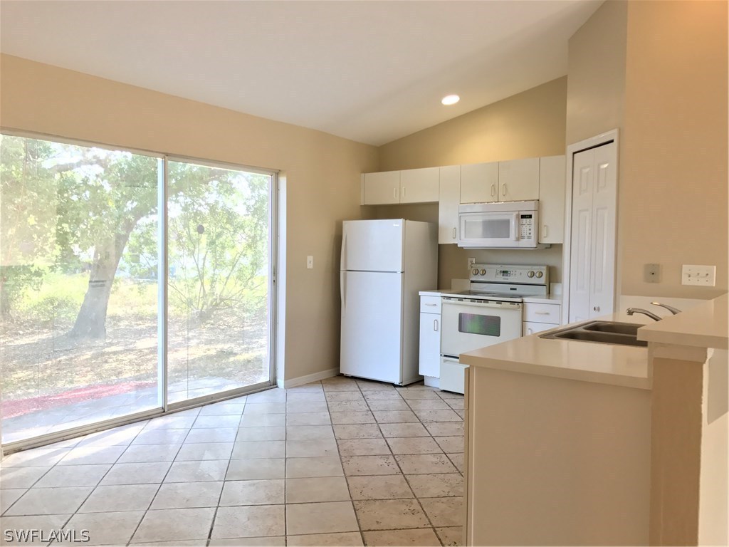 4458 28th Street Southwest Lehigh Acres, FL 33973 - Photo 8 of 22 a kitchen with a refrigerator a stove top oven and a large window