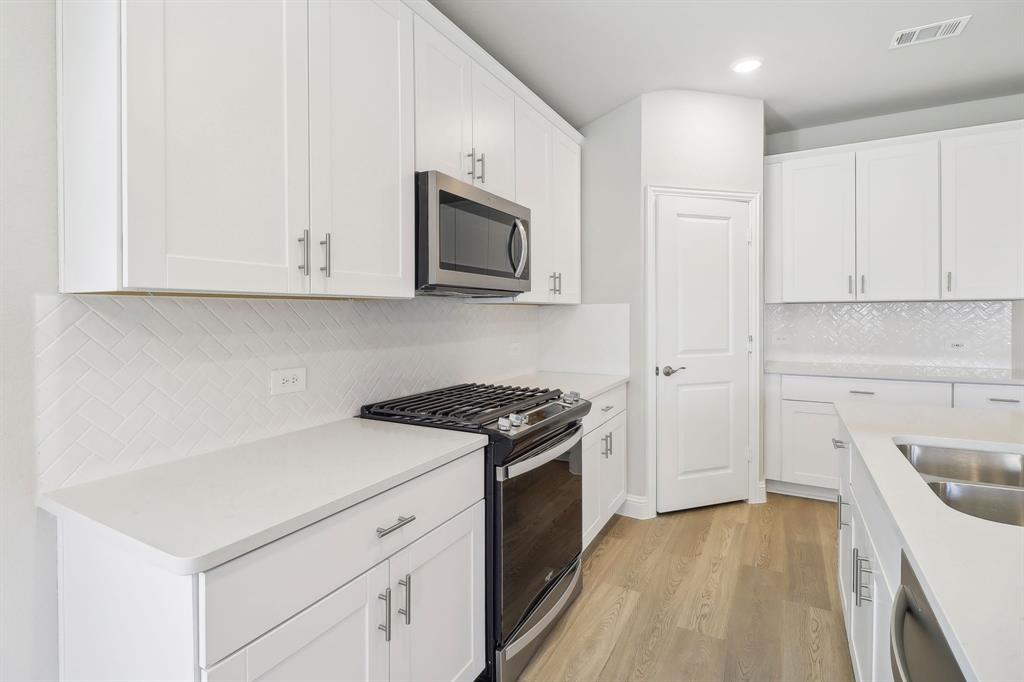 905 Buffalo Drive Lowry Crossing, TX 75407 - Photo 3 of 28 a kitchen with white cabinets and black appliances
