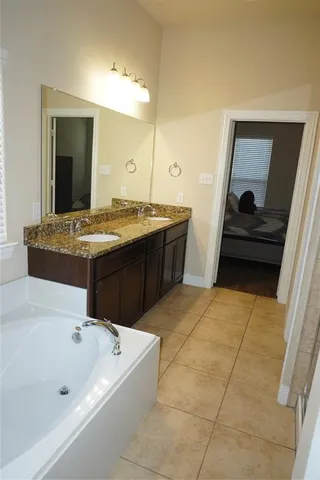 a spacious bathroom with a tub sink and mirror