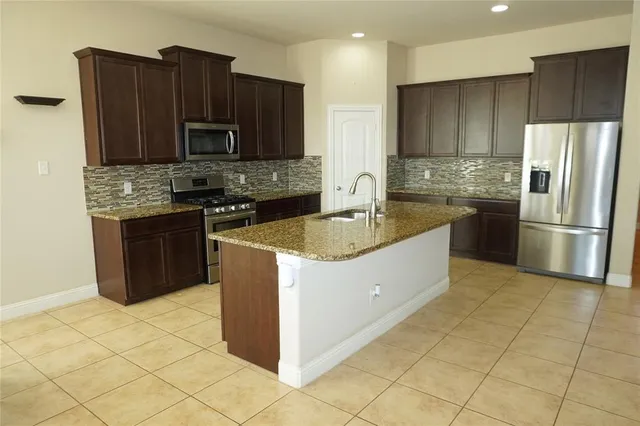 a kitchen with stainless steel appliances granite countertop a stove a refrigerator and a sink