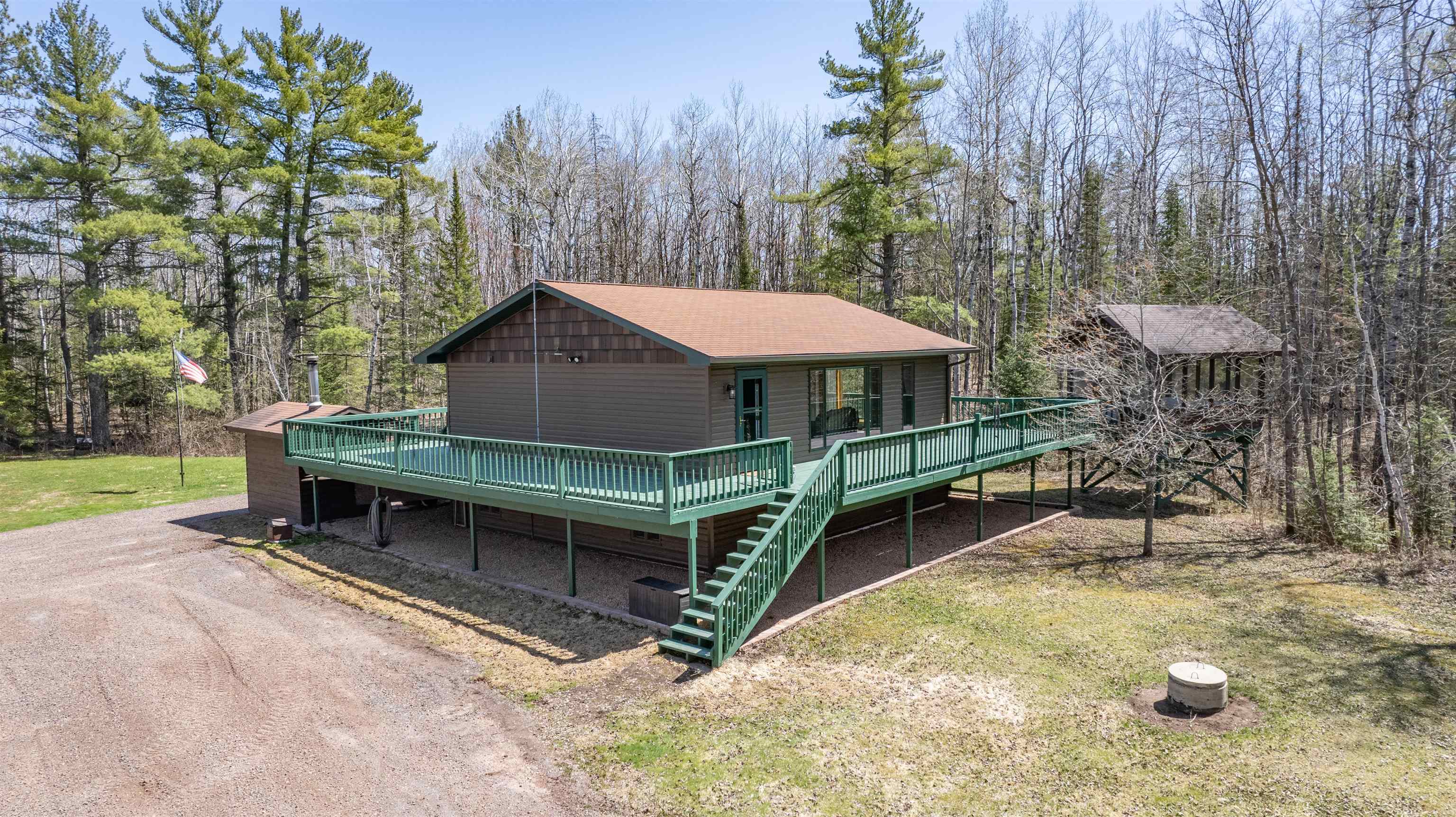 Chalet / cabin featuring a deck, stairs, and a view of trees