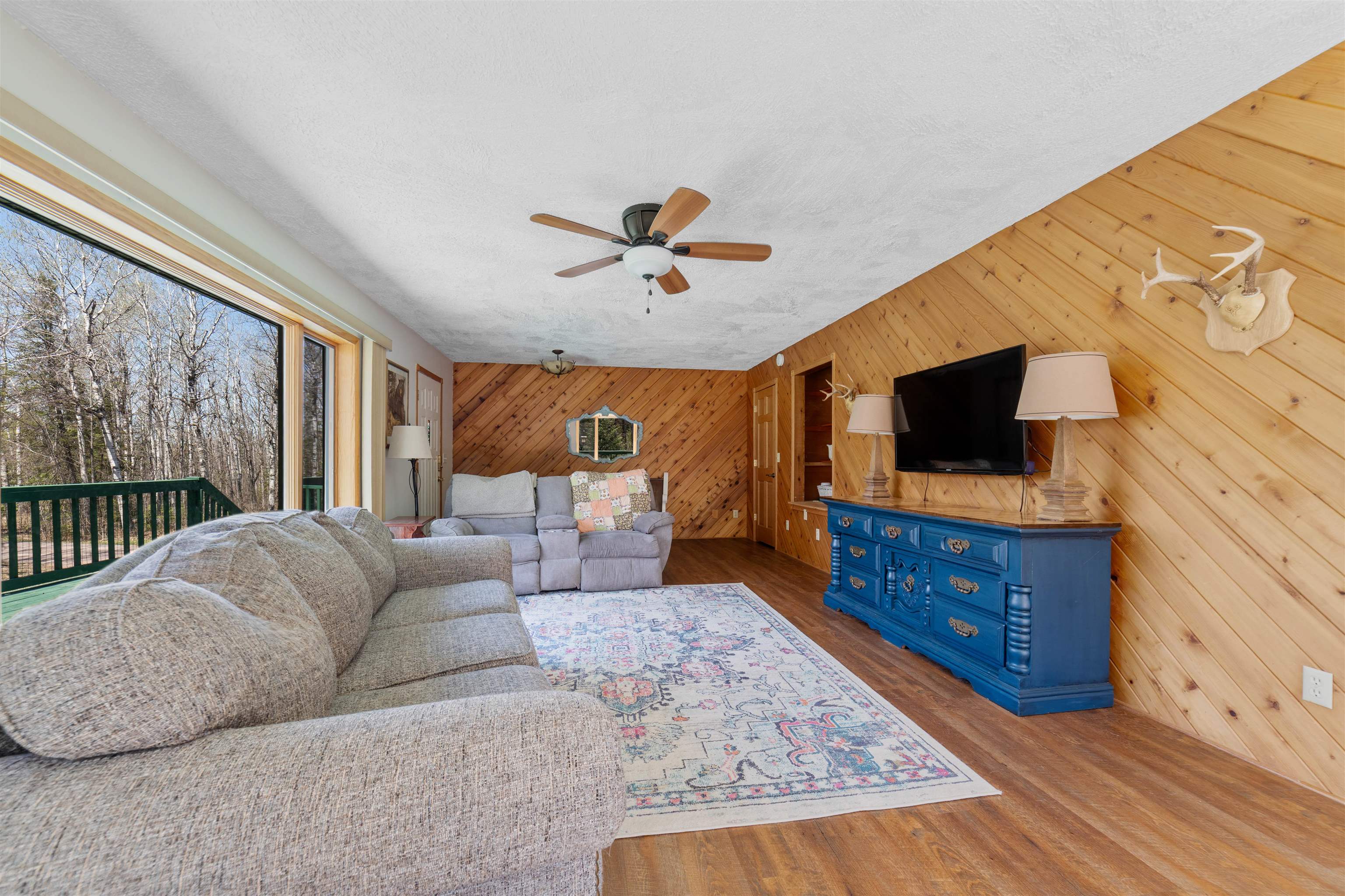 6960 South County Rd B Foxboro, WI 54836 - Photo 6 of 28 Living area with wooden walls, a ceiling fan, wood finished floors, and a textured ceiling