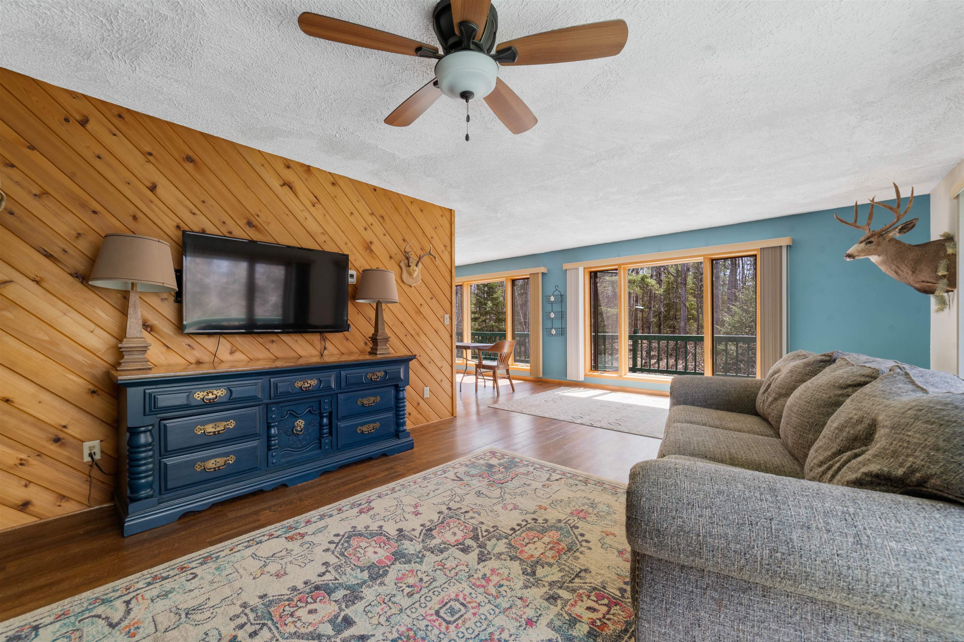 6960 South County Rd B Foxboro, WI 54836 - Photo 7 of 28 Living area featuring a textured ceiling, dark wood-type flooring, wooden walls, and ceiling fan