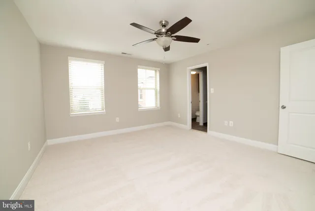 an empty room with windows and ceiling fan