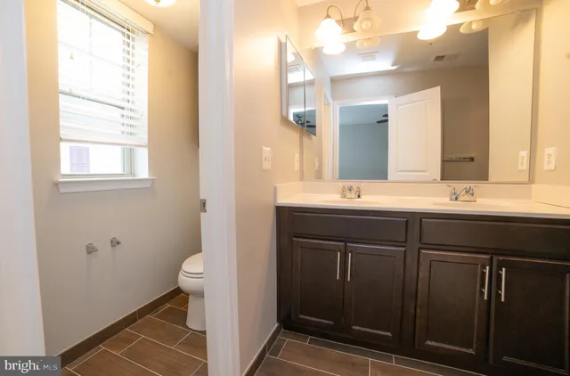 a bathroom with a sink a toilet a mirror and a window