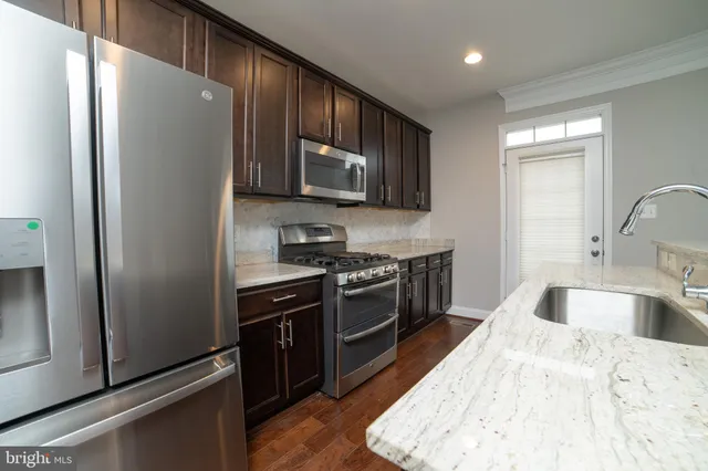 a kitchen with stainless steel appliances granite countertop a refrigerator stove and sink