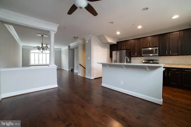 a kitchen with stainless steel appliances granite countertop a refrigerator a sink dishwasher a stove and a oven with wooden floor