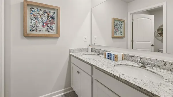 a bathroom with a granite countertop double vanity sink and a mirror